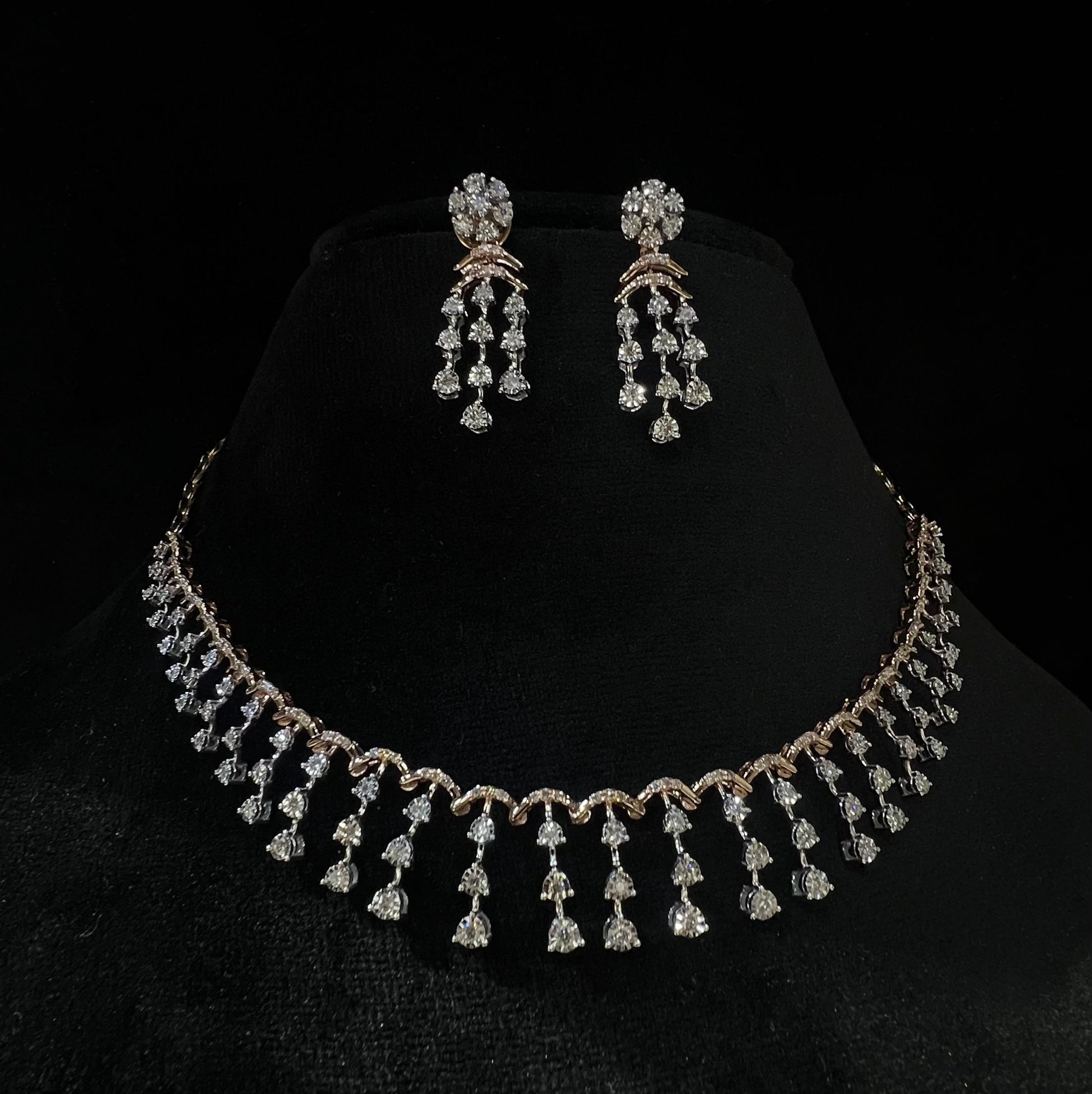 A gold diamond necklace with a series of round and marquise shaped earrings attached to the neckline, set on a black mannequin.