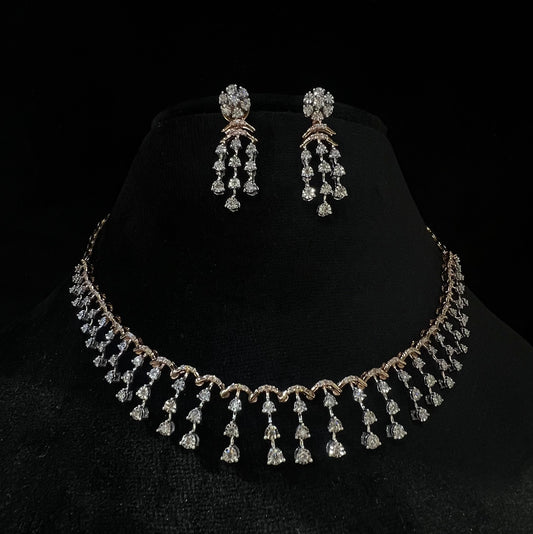 A gold diamond necklace with a series of round and marquise shaped earrings attached to the neckline, set on a black mannequin.