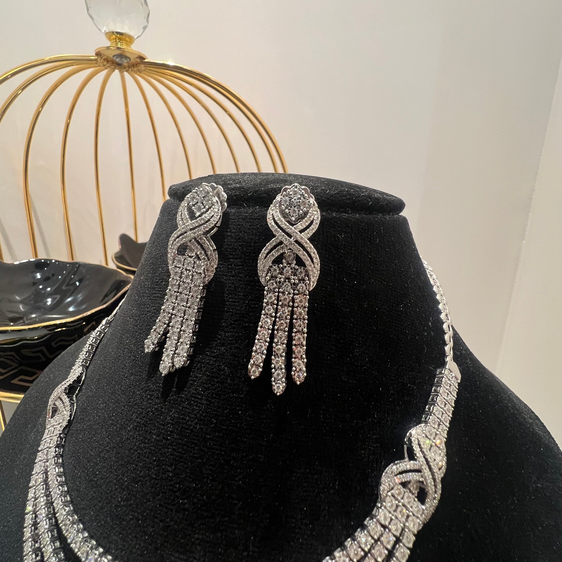 Eternal Knot Cascade diamond necklace set with matching earrings featuring layered diamond strands displayed on a mannequin.