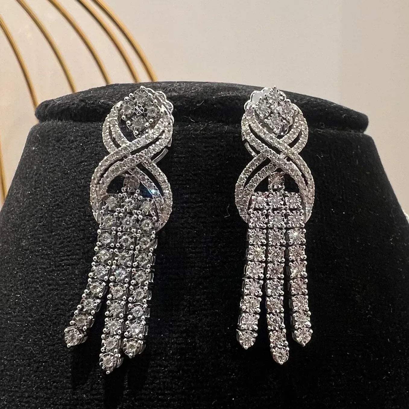 Eternal Knot Cascade diamond necklace set with matching earrings featuring layered diamond strands displayed on a mannequin.