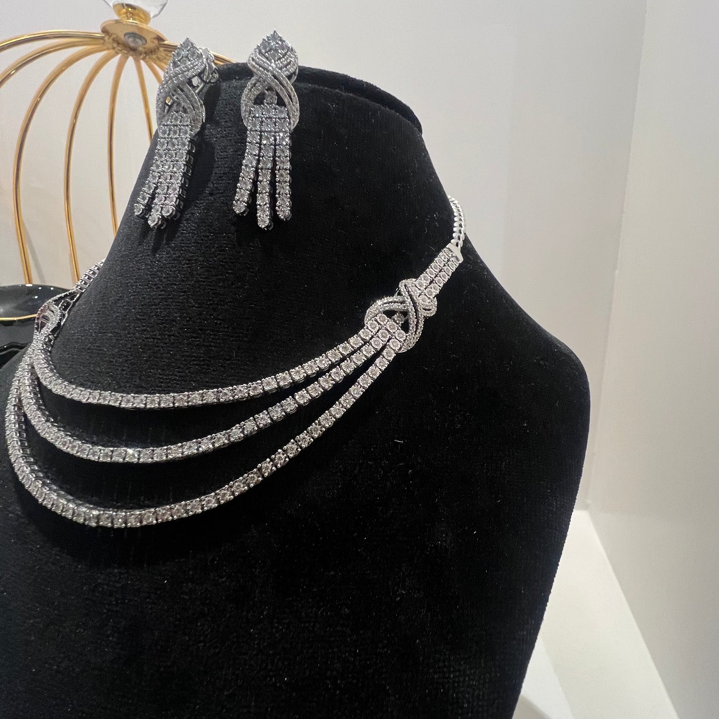 Eternal Knot Cascade diamond necklace set with matching earrings featuring layered diamond strands displayed on a mannequin.