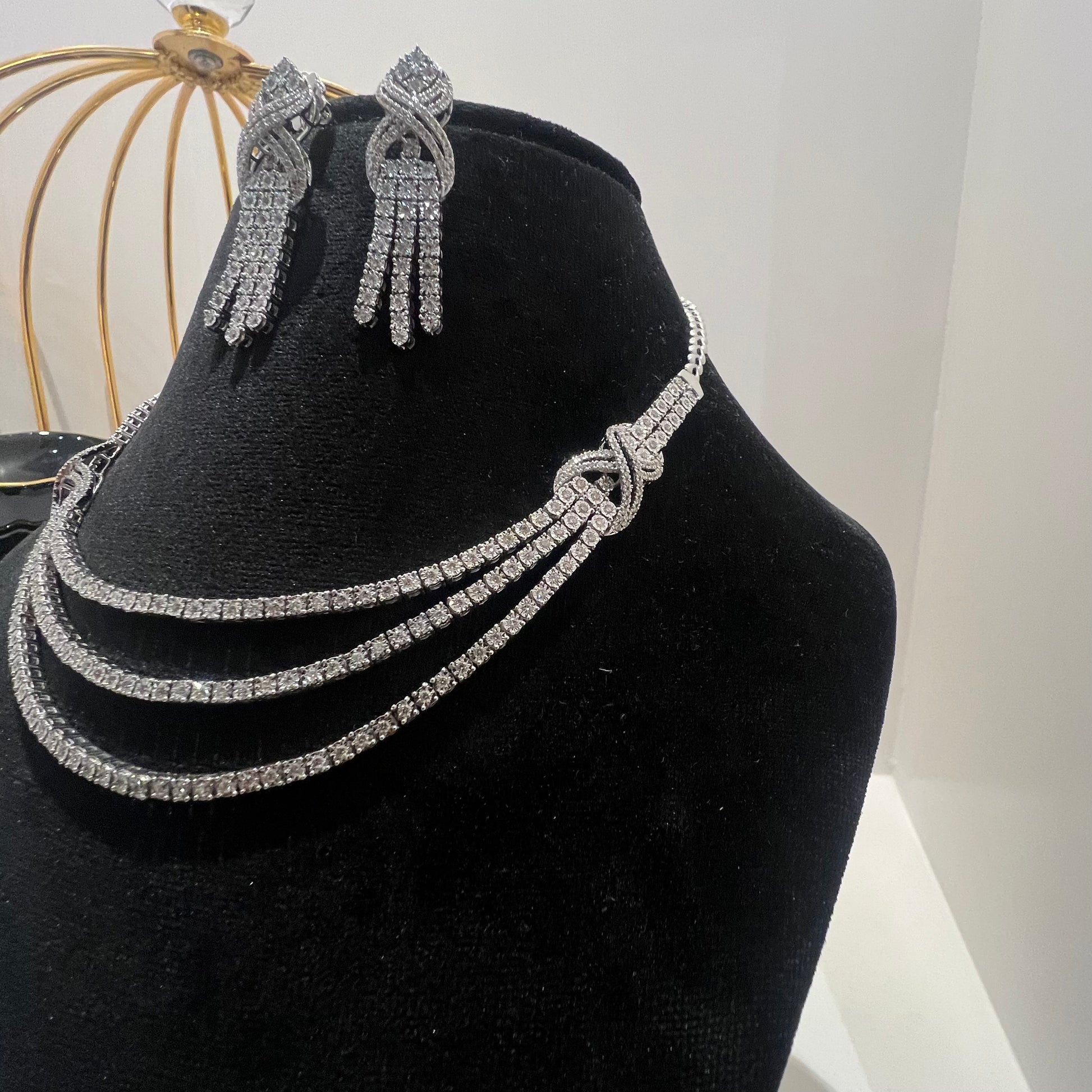 Eternal Knot Cascade diamond necklace set with matching earrings featuring layered diamond strands displayed on a mannequin.
