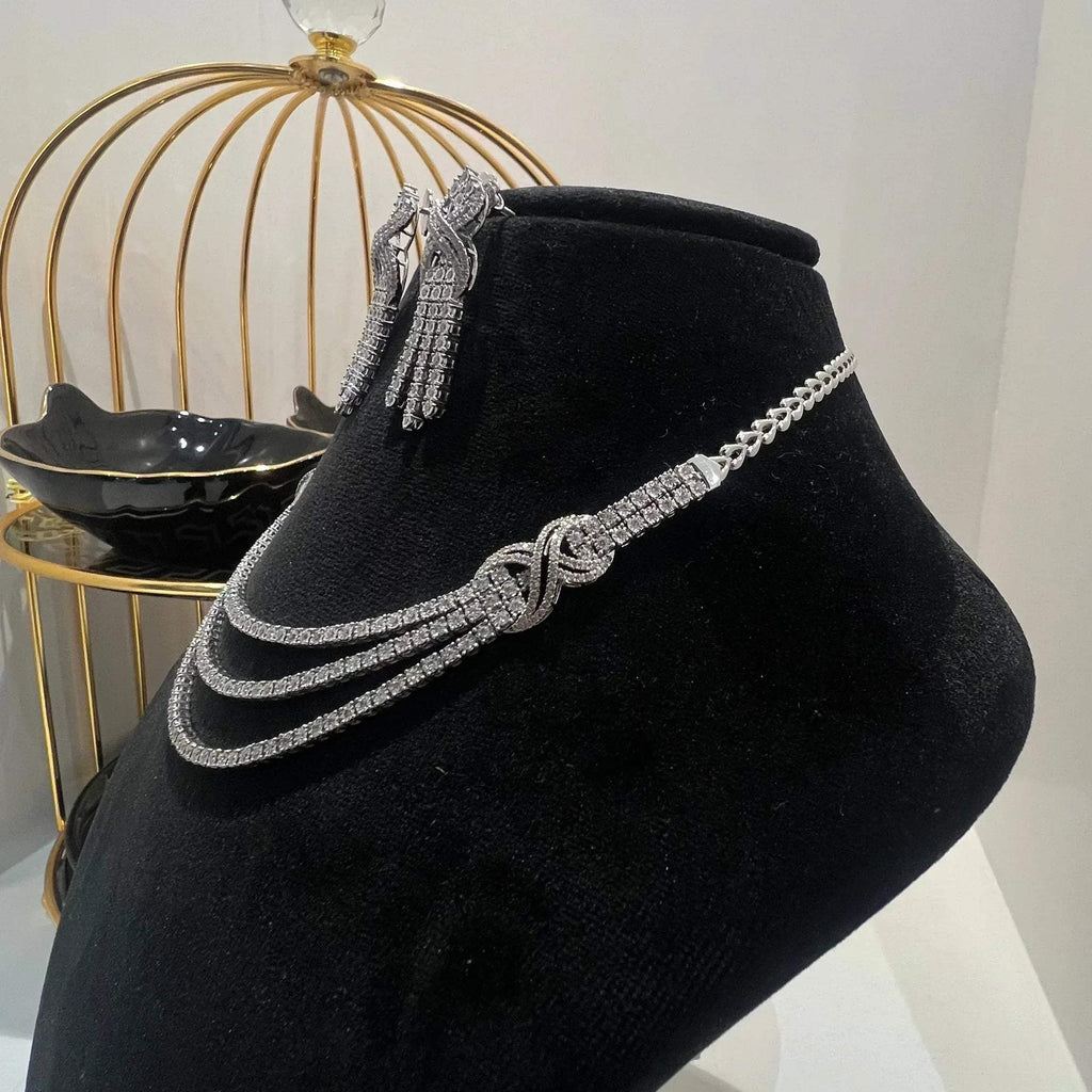 Eternal Knot Cascade diamond necklace set with matching earrings featuring layered diamond strands displayed on a mannequin from left side.