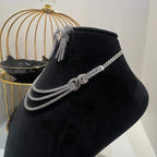 Eternal Knot Cascade diamond necklace set with matching earrings featuring layered diamond strands displayed on a mannequin from left side.