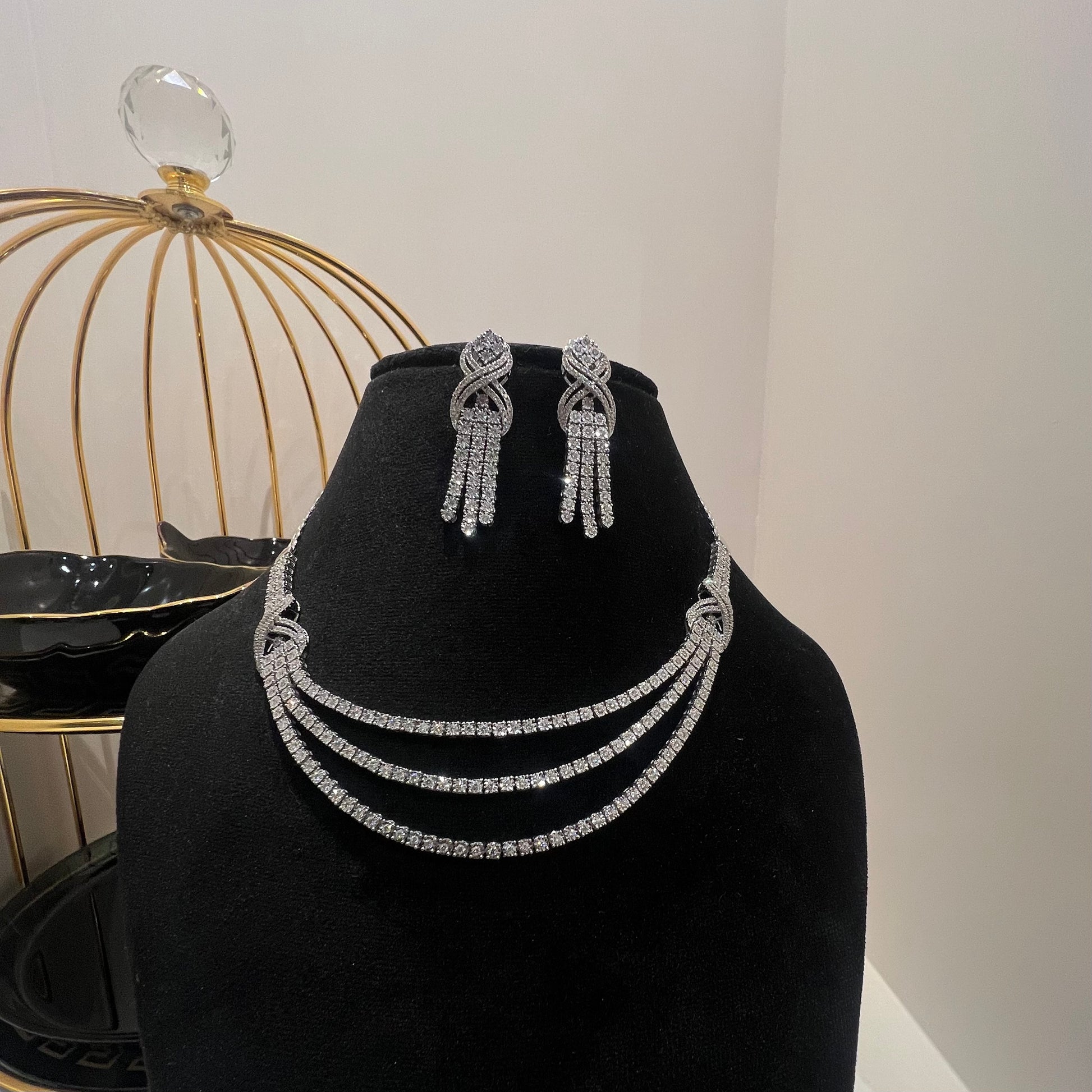 Eternal Knot Cascade diamond necklace set with matching earrings featuring layered diamond strands displayed on a mannequin.