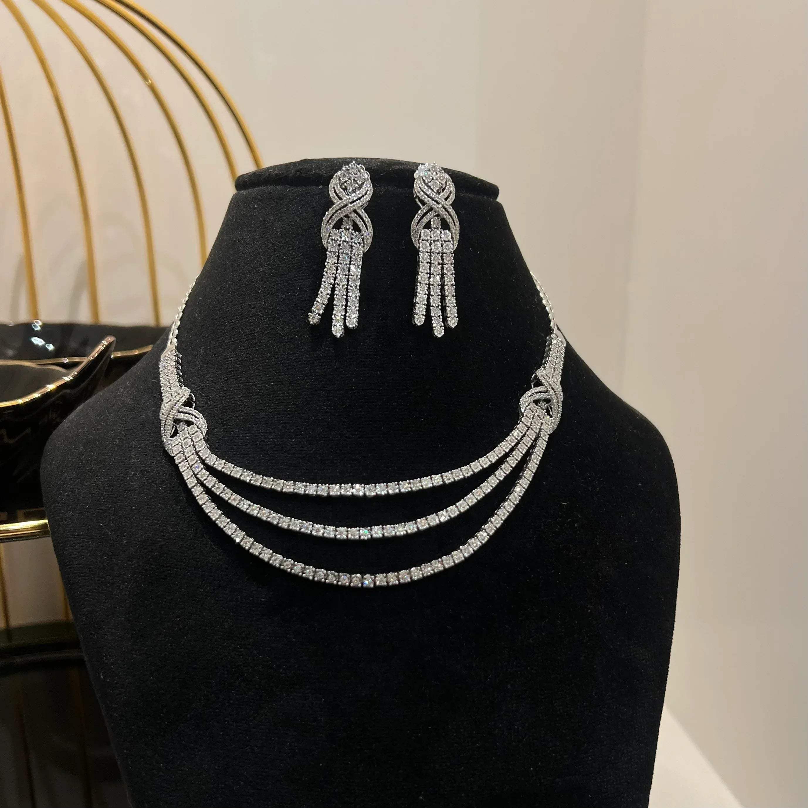 Eternal Knot Cascade diamond necklace set with matching earrings featuring layered diamond strands displayed on a mannequin.