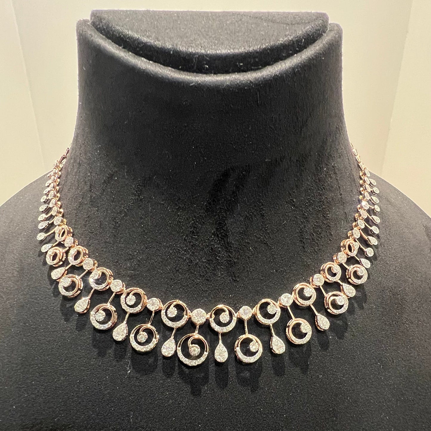 A gold diamond necklace and earrings set displayed on a mannequin bust, featuring a floral design with intricate detailing and adorned with genuine diamonds.