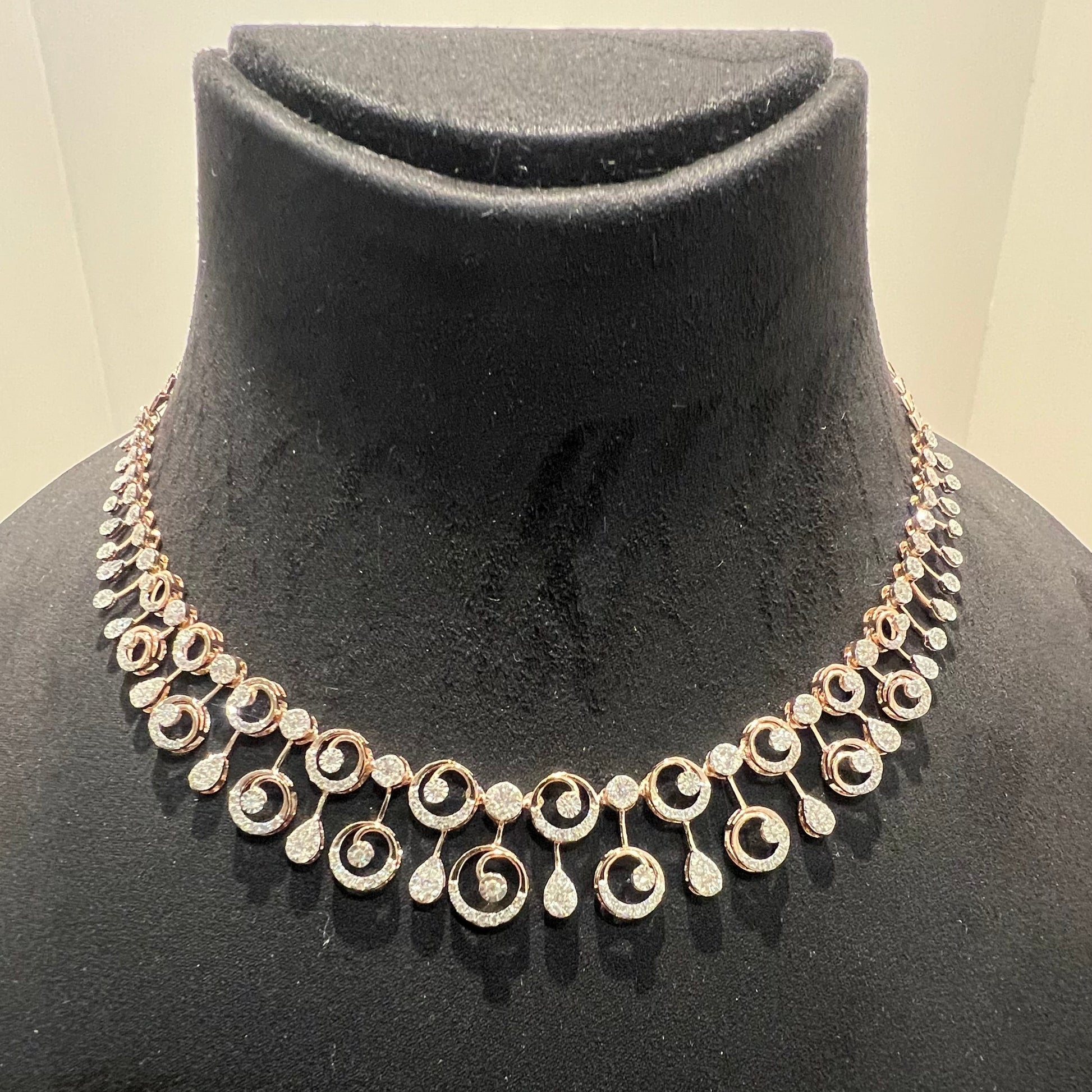 A gold diamond necklace and earrings set displayed on a mannequin bust, featuring a floral design with intricate detailing and adorned with genuine diamonds.
