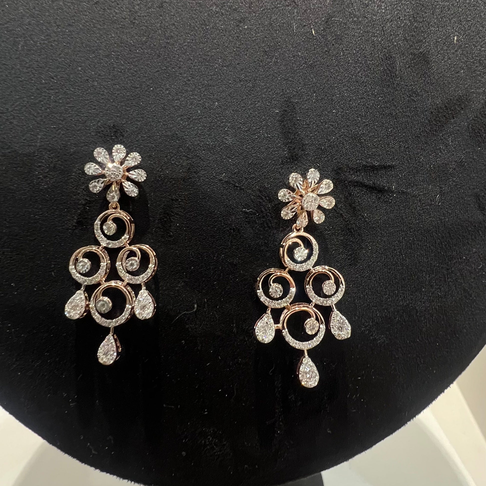 gold diamond earrings displayed on a mannequin bust, featuring a floral design with intricate detailing and adorned with genuine diamonds.
