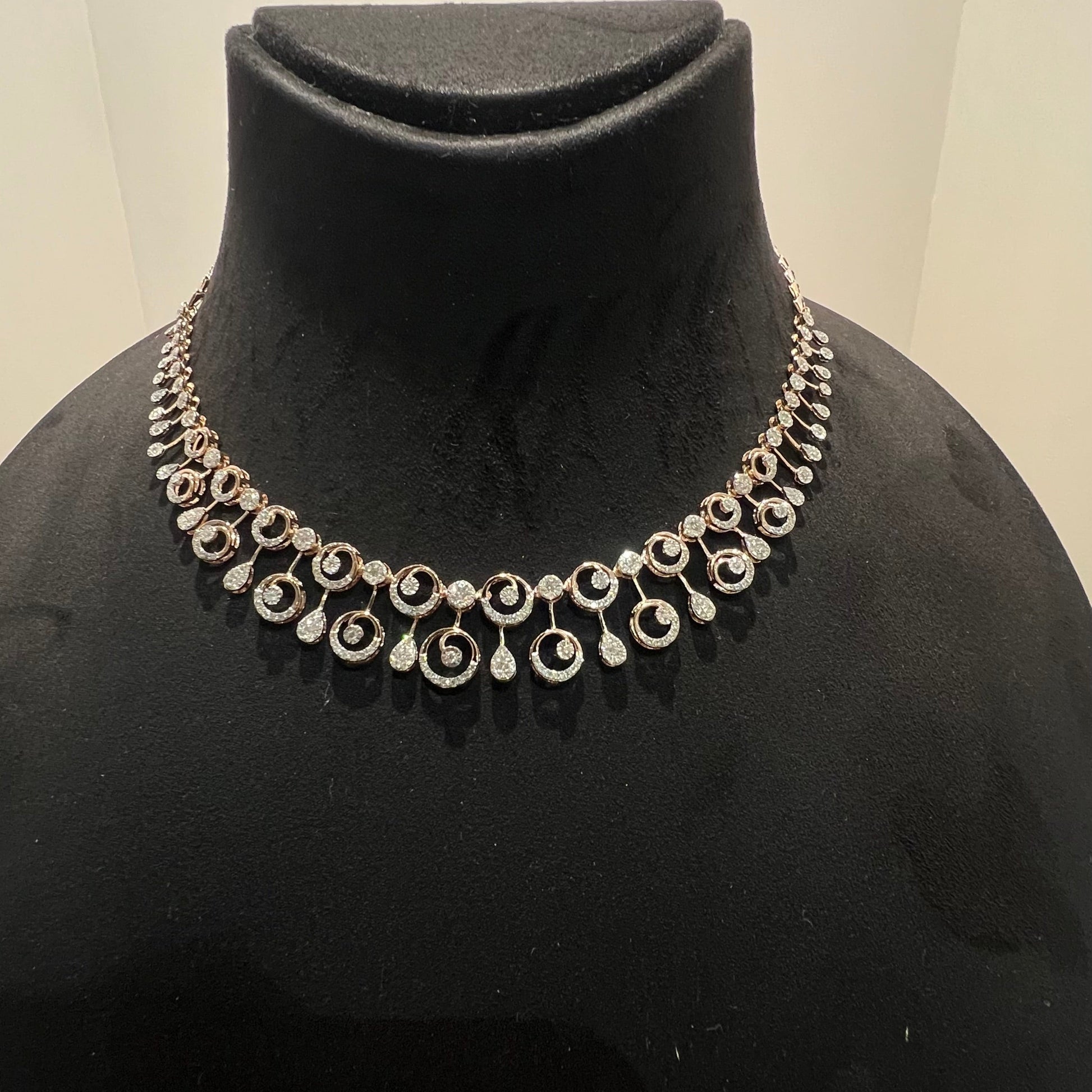 A gold diamond necklace displayed on a mannequin bust, featuring a floral design with intricate detailing and adorned with genuine diamonds.