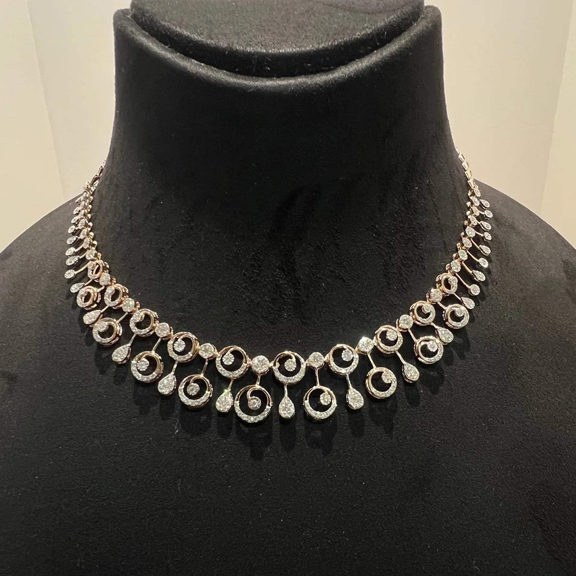 A gold diamond necklace displayed on a mannequin bust, featuring a floral design with intricate detailing and adorned with genuine diamonds.