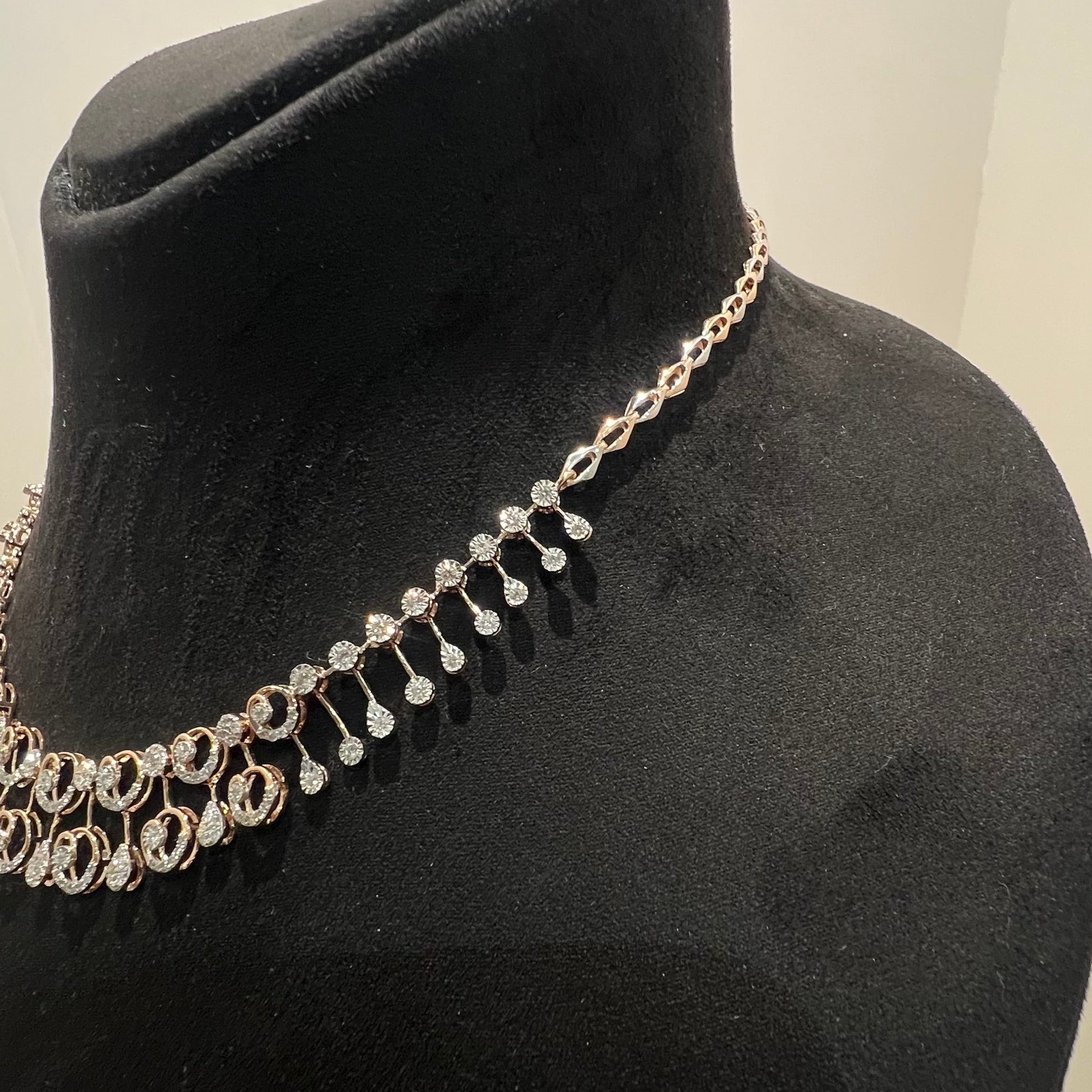 A gold diamond necklace displayed on a mannequin bust, featuring a floral design with intricate detailing and adorned with genuine diamonds.