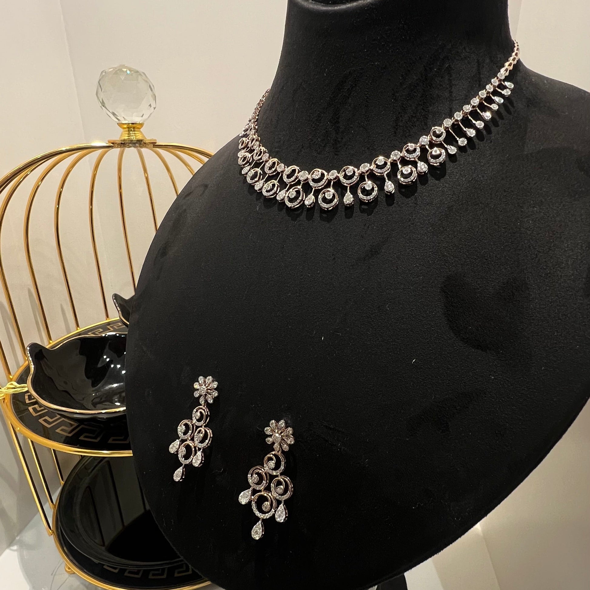 A gold diamond necklace and earrings set displayed on a mannequin bust, featuring a floral design with intricate detailing and adorned with genuine diamonds.