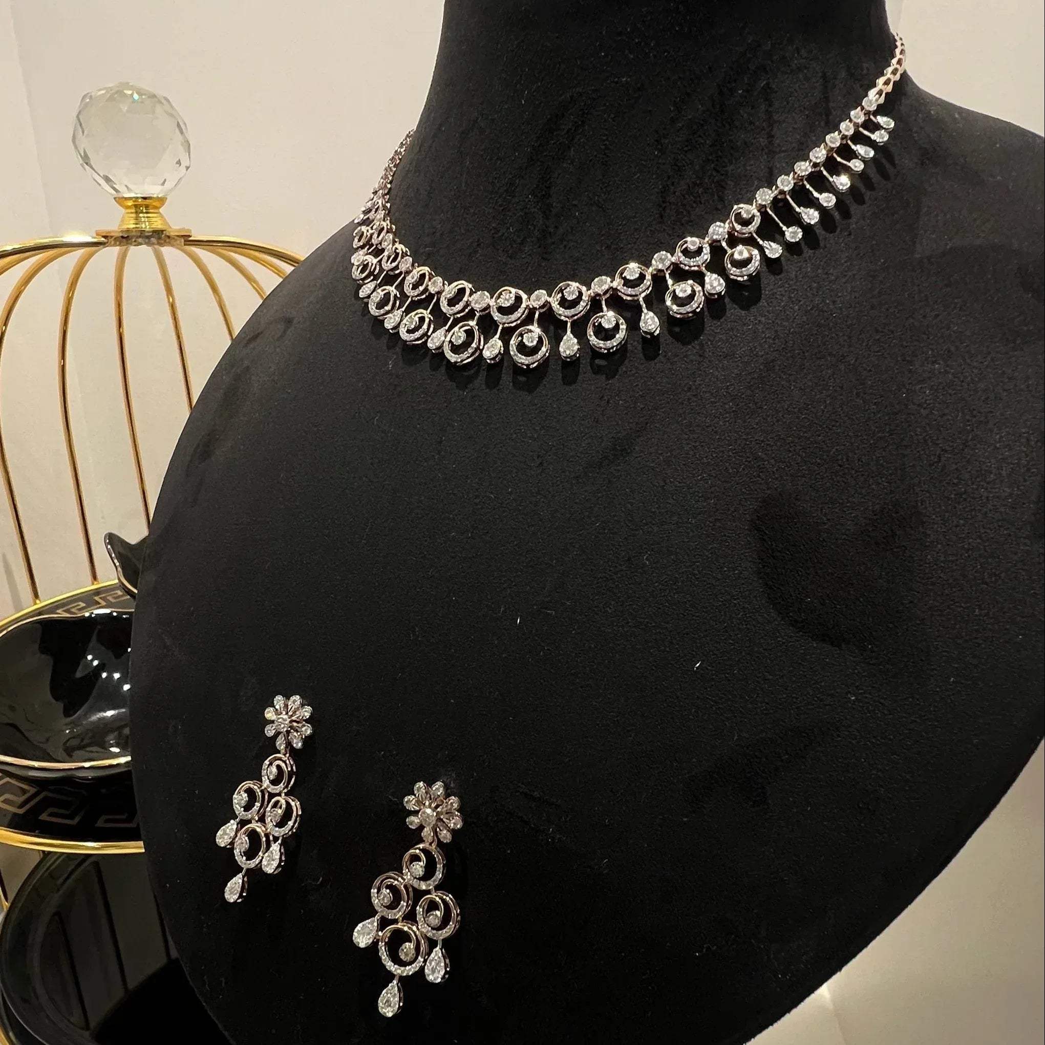 A gold diamond necklace and earrings set displayed on a mannequin bust, featuring a floral design with intricate detailing and adorned with genuine diamonds.