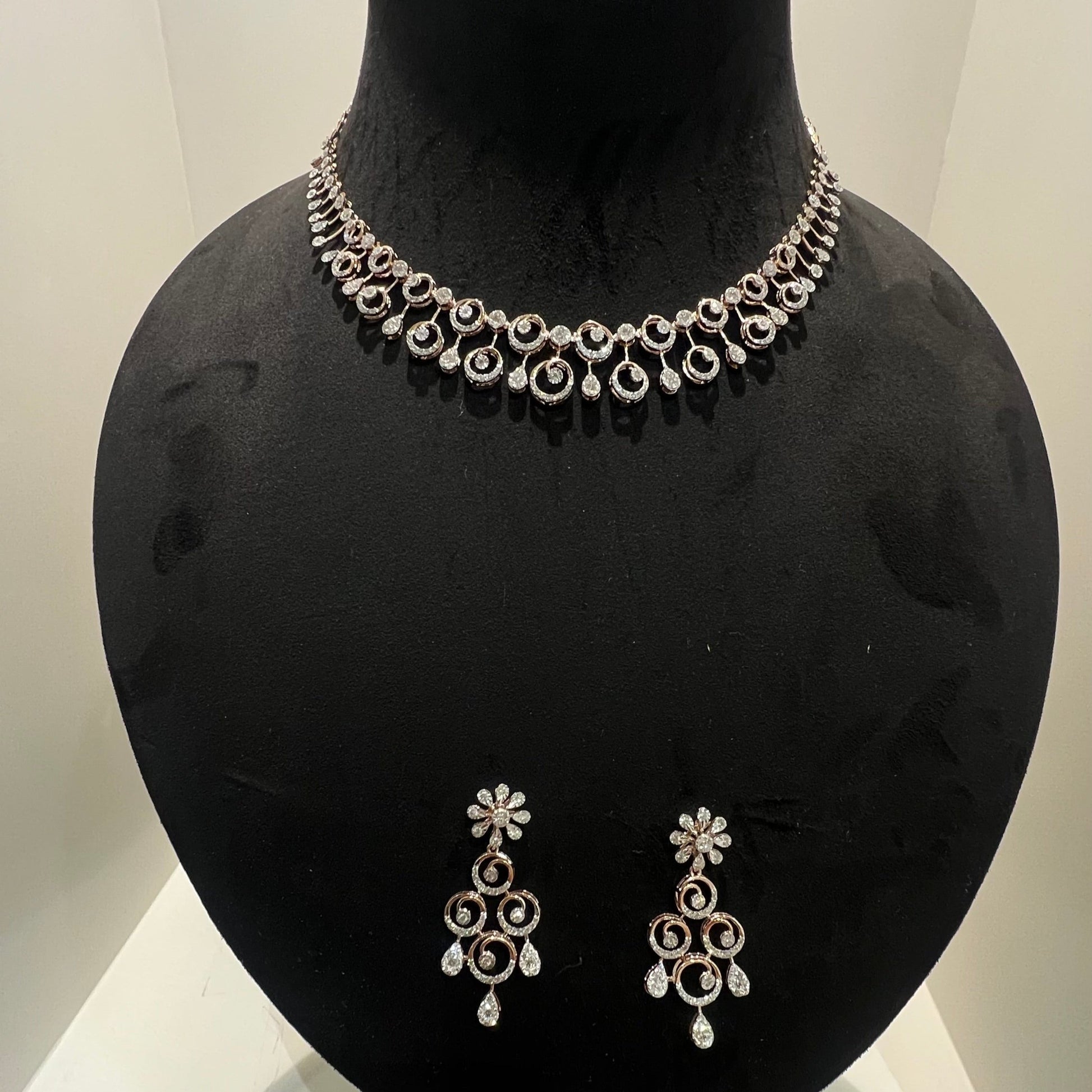 A gold diamond necklace and earrings set displayed on a mannequin bust, featuring a floral design with intricate detailing and adorned with genuine diamonds.