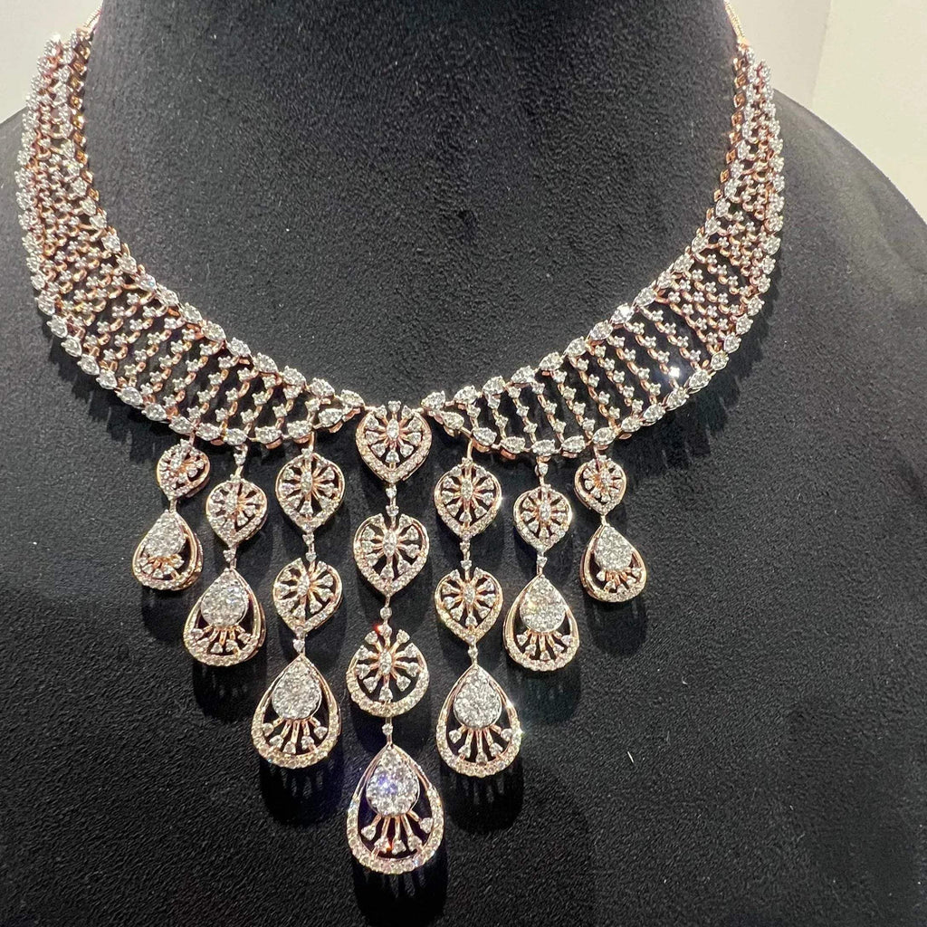 A gold diamond necklace with a geometric pattern and a pair of matching earrings, displayed on a mannequin bust.