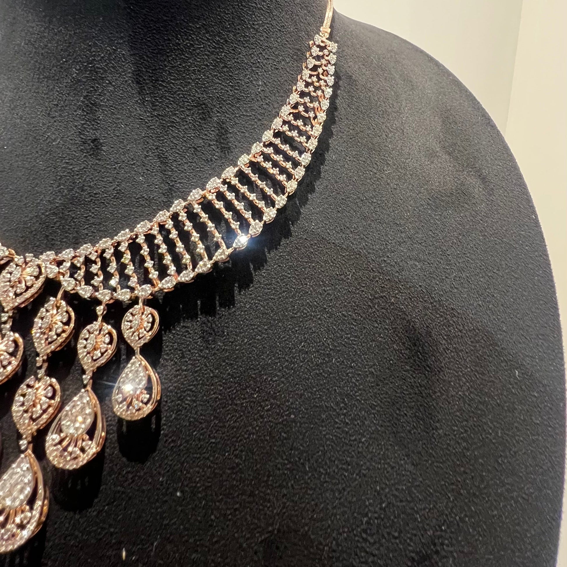 A gold diamond necklace with a geometric pattern, displayed on a mannequin bust.