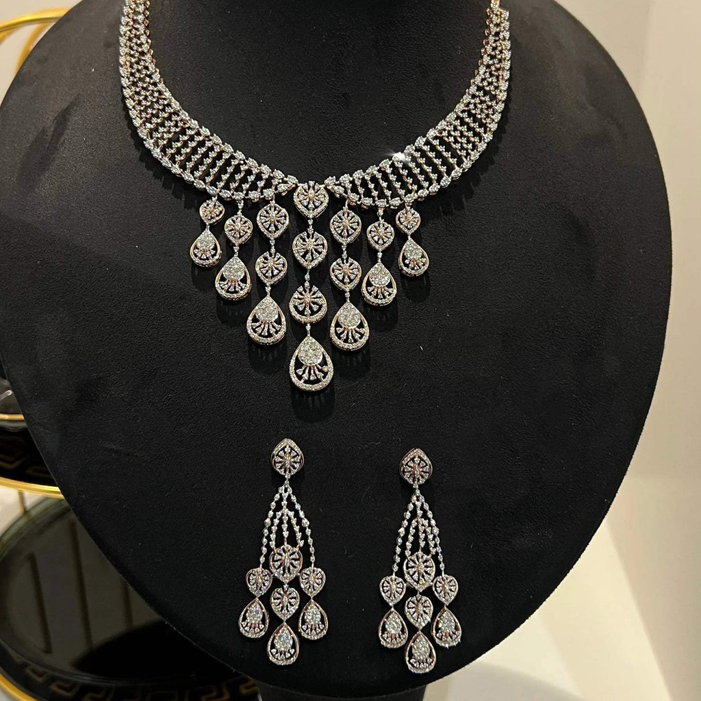 A gold diamond necklace with a geometric pattern and a pair of matching earrings, displayed on a mannequin bust.