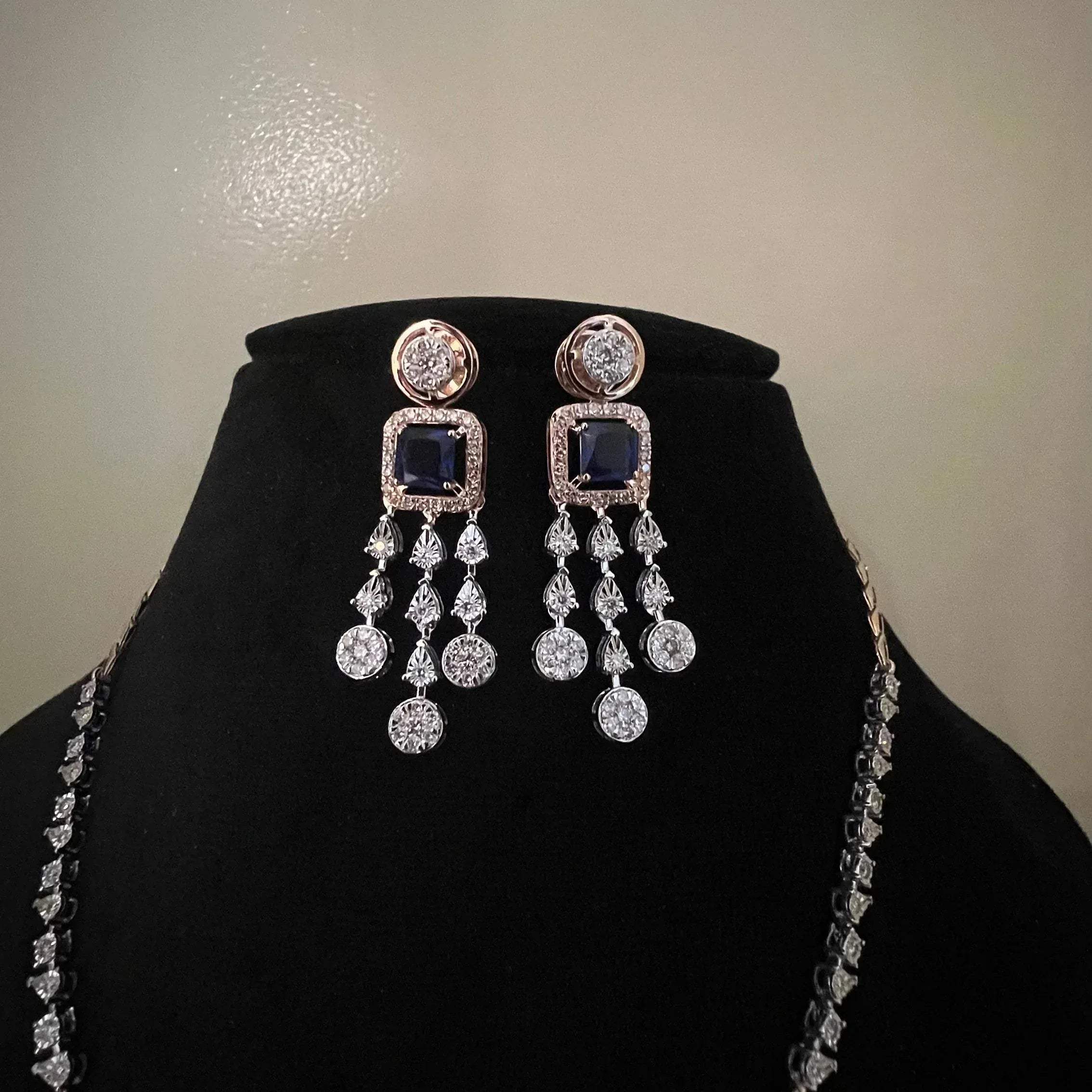 A gold diamond necklace with a matching set of earrings, featuring a series of round and marquise shaped diamonds set in a classic design on a mannequin bust.