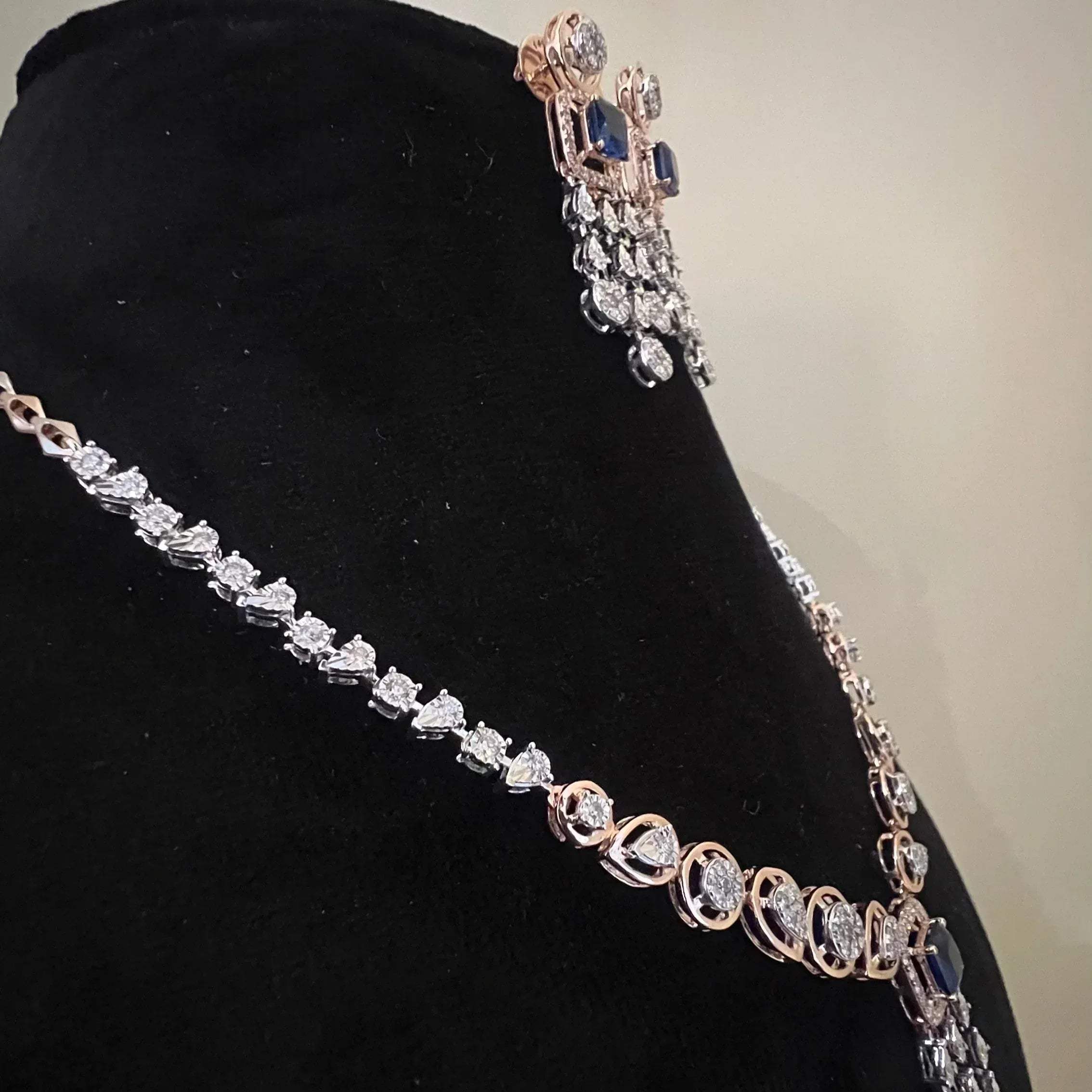 A gold diamond necklace with a matching set of earrings, featuring a series of round and marquise shaped diamonds set in a classic design on a mannequin bust.