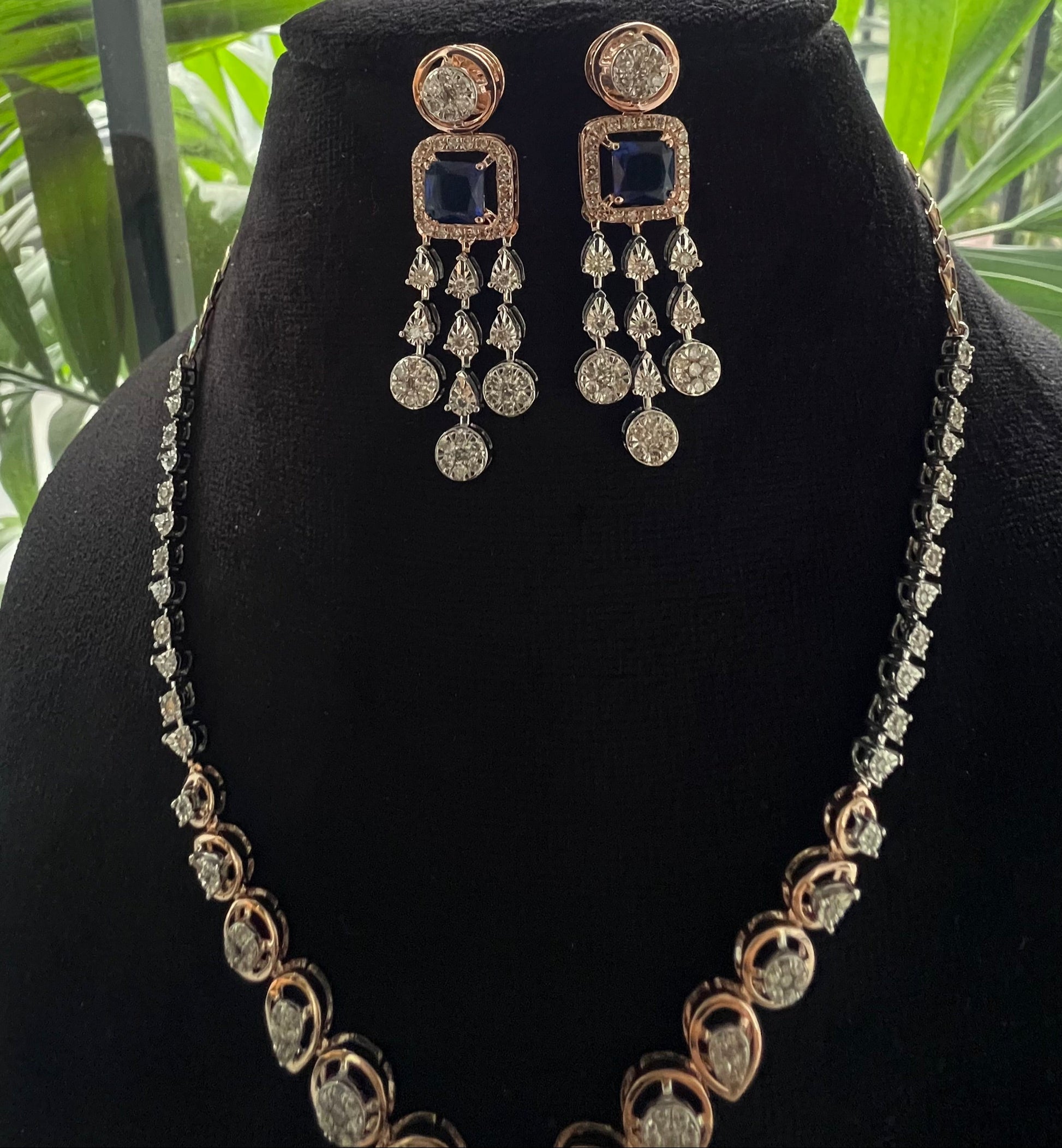 A gold diamond necklace with a matching set of earrings, featuring a series of round and marquise shaped diamonds set in a classic design on a mannequin bust.