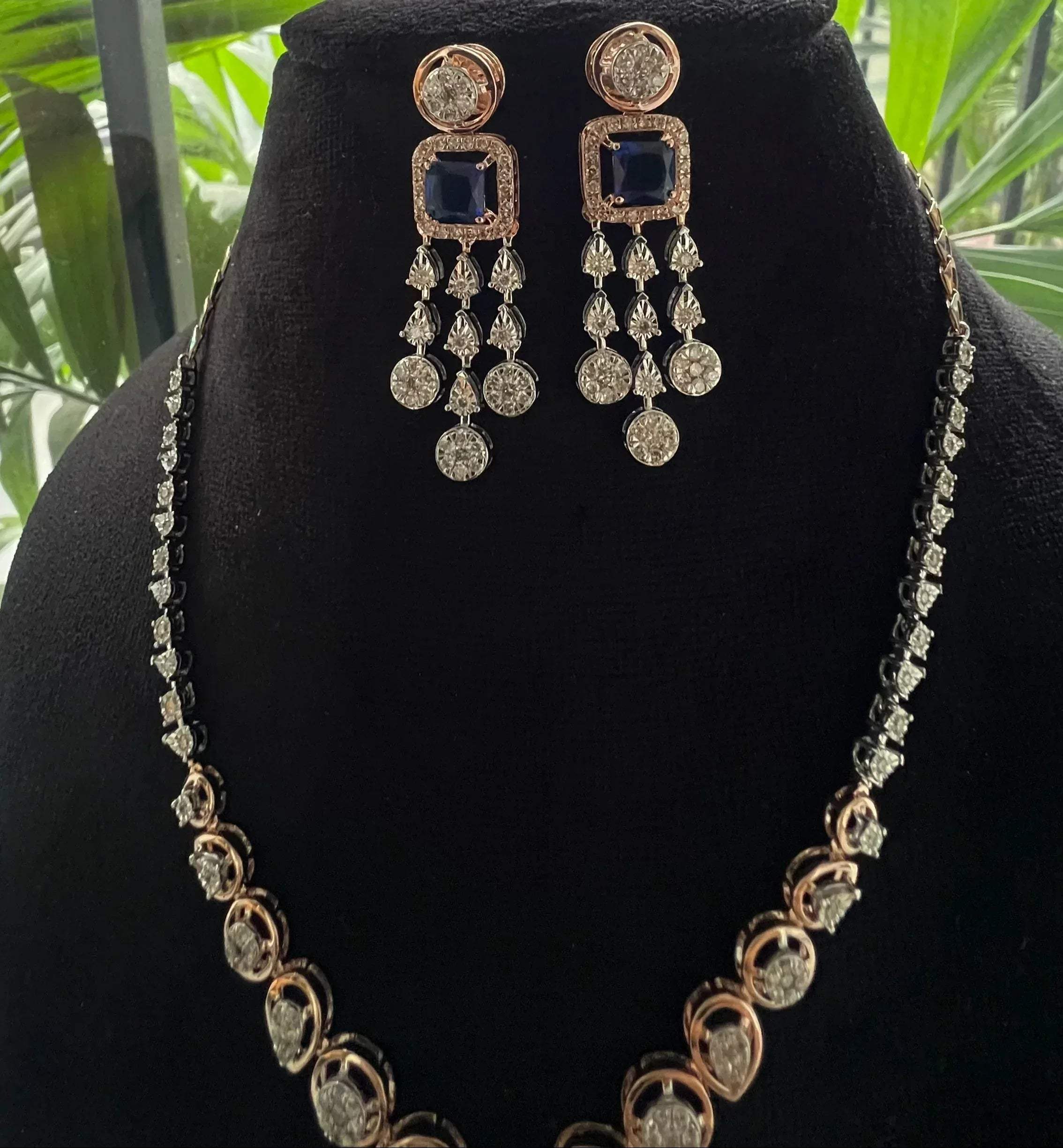 A gold diamond necklace with a matching set of earrings, featuring a series of round and marquise shaped diamonds set in a classic design on a mannequin bust.