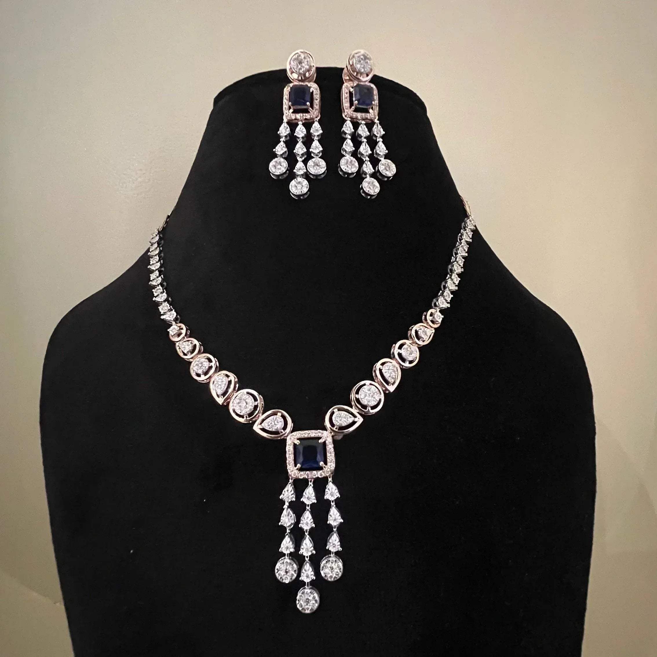A gold diamond necklace with a matching set of earrings, featuring a series of round and marquise shaped diamonds set in a classic design on a mannequin bust.