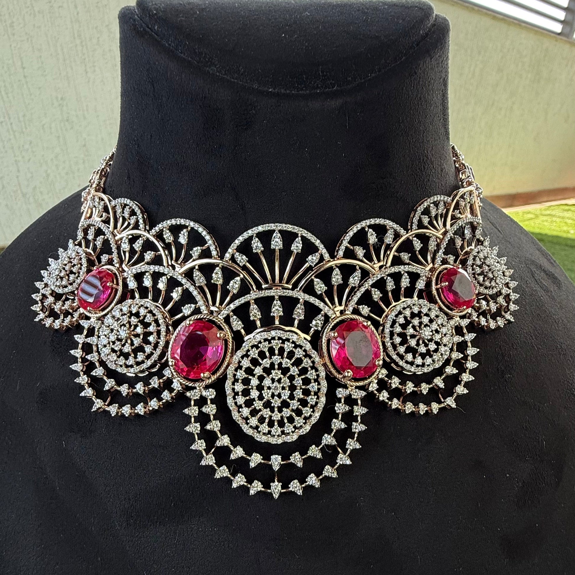 A gold diamond choker necklace with a floral pattern and red and white diamonds, displayed on a mannequin.