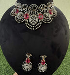 A gold diamond choker necklace with a floral pattern and red and white diamonds, accompanied by matching earrings, displayed on a mannequin.