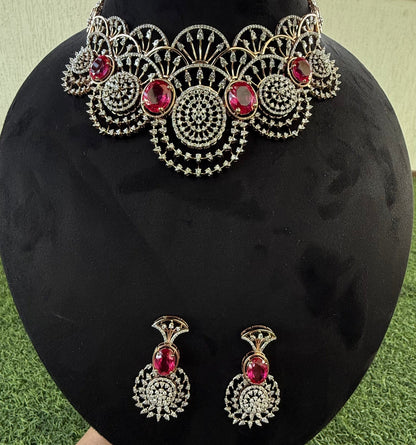A gold diamond choker necklace with a floral pattern and red and white diamonds, accompanied by matching earrings, displayed on a mannequin.