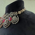 A gold diamond choker necklace with a floral pattern and red and white diamonds, displayed on a mannequin from left side.