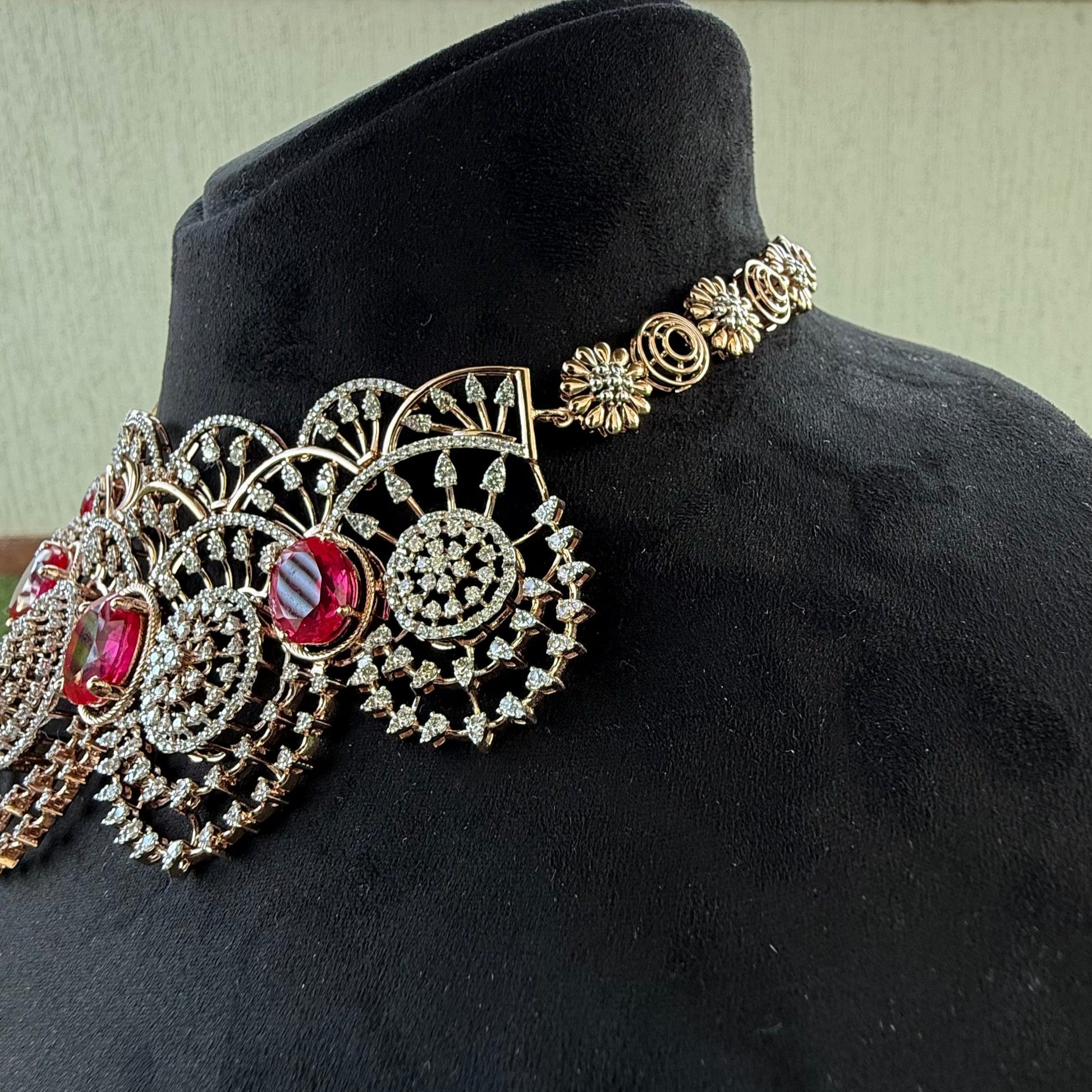 A gold diamond choker necklace with a floral pattern and red and white diamonds, displayed on a mannequin from left side.