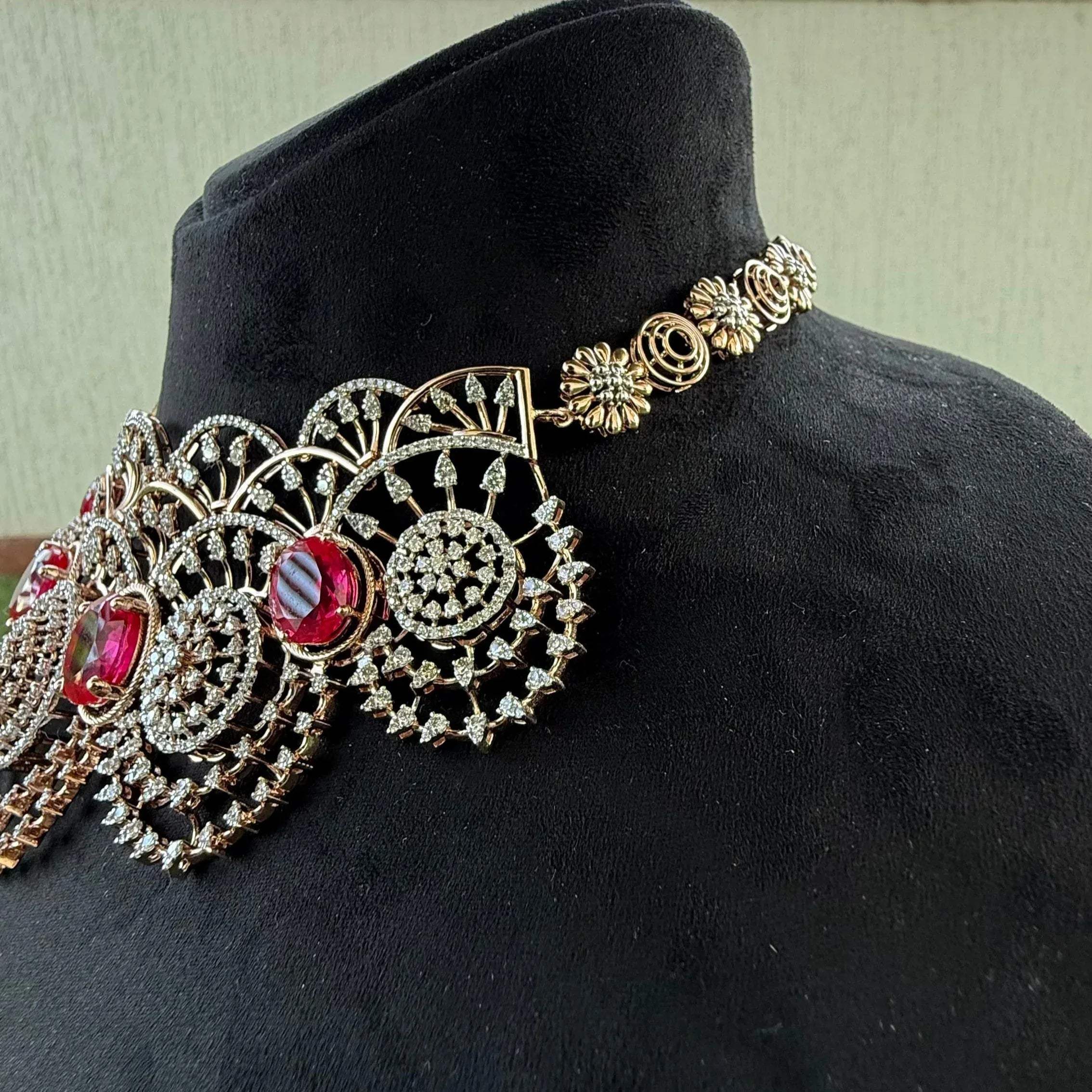 A gold diamond choker necklace with a floral pattern and red and white diamonds, displayed on a mannequin from left side.