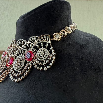 A gold diamond choker necklace with a floral pattern and red and white diamonds, displayed on a mannequin from left side.