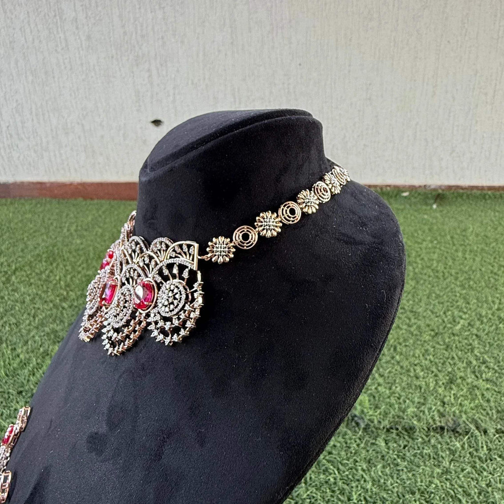 A gold diamond choker necklace with a floral pattern and red and white diamonds, displayed on a mannequin.