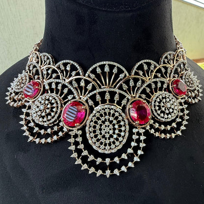 A gold diamond choker necklace with a floral pattern and red and white diamonds, accompanied by matching earrings, displayed on a mannequin.
