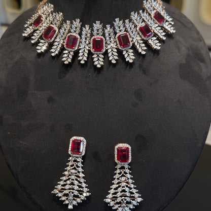 Diamond necklace set with emerald-cut color stones and leaf-shaped diamond clusters, paired with matching color stone and diamond earrings is displayed on a mannequin.