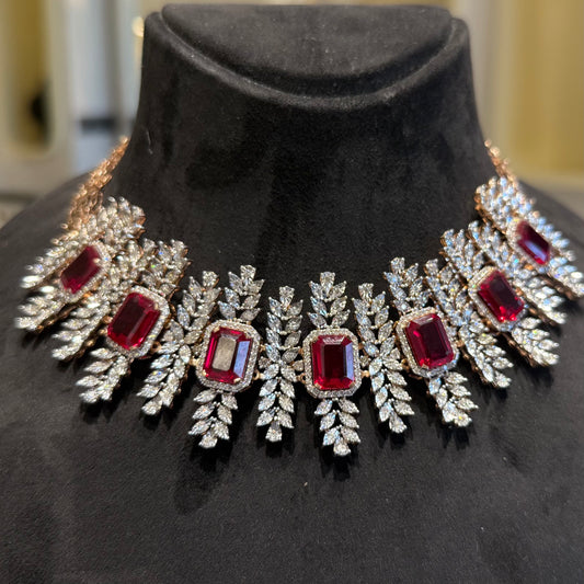 Diamond necklace set with emerald-cut color stones and leaf-shaped diamond clusters is displayed on a mannequin.