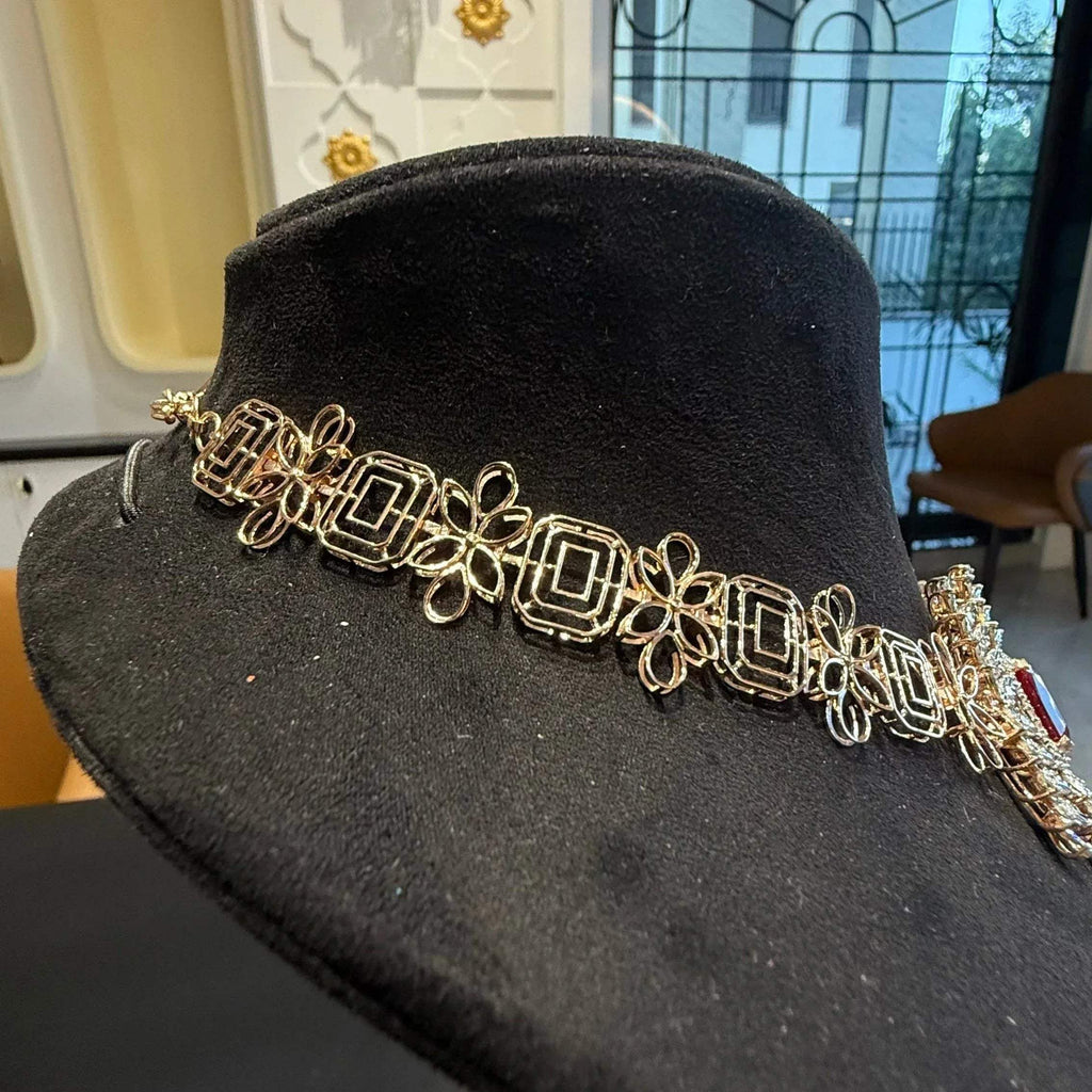 Diamond necklace set with emerald-cut color stones and leaf-shaped diamond clusters is displayed on a mannequin from back side.