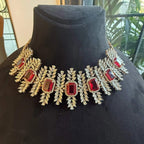 Diamond necklace set with emerald-cut color stones and leaf-shaped diamond clusters is displayed on a mannequin from front side.
