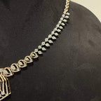 A gold diamond necklace with a geometric pendant displayed on a mannequin bust.