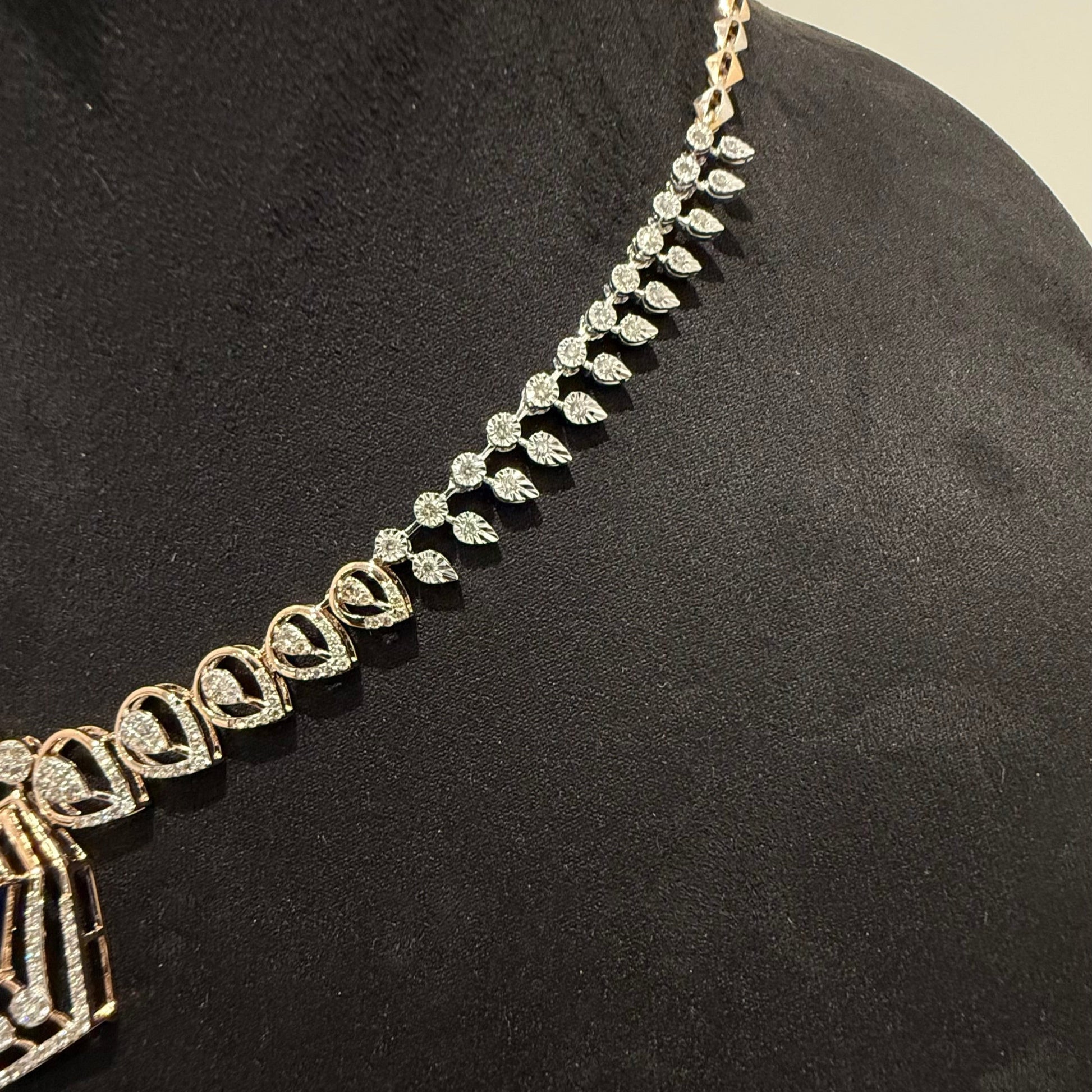 A gold diamond necklace with a geometric pendant displayed on a mannequin bust.