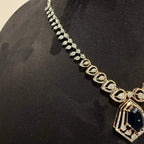 A gold diamond necklace with a geometric pendant displayed on a mannequin bust.