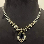 A gold diamond necklace with a geometric pendant displayed on a mannequin bust.