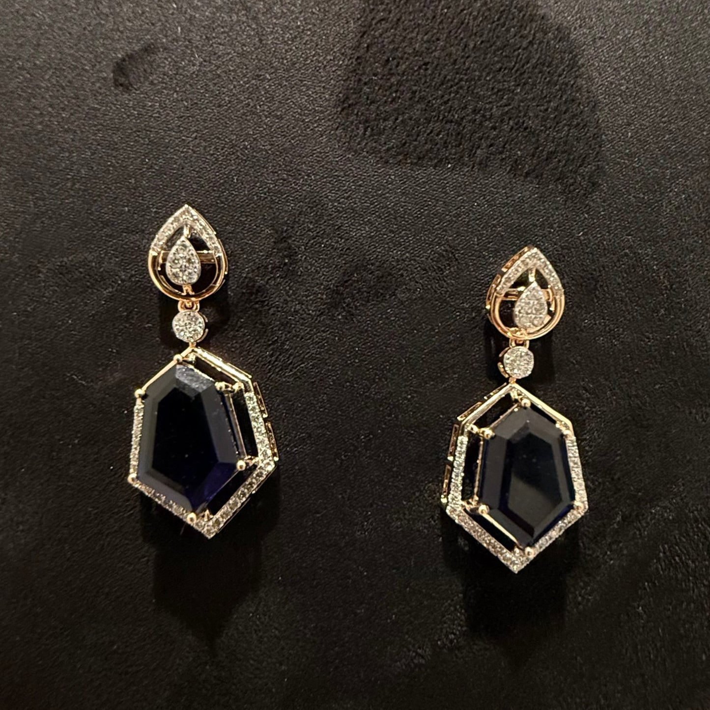A gold diamond necklace with a geometric pendant and matching earrings displayed on a mannequin bust.