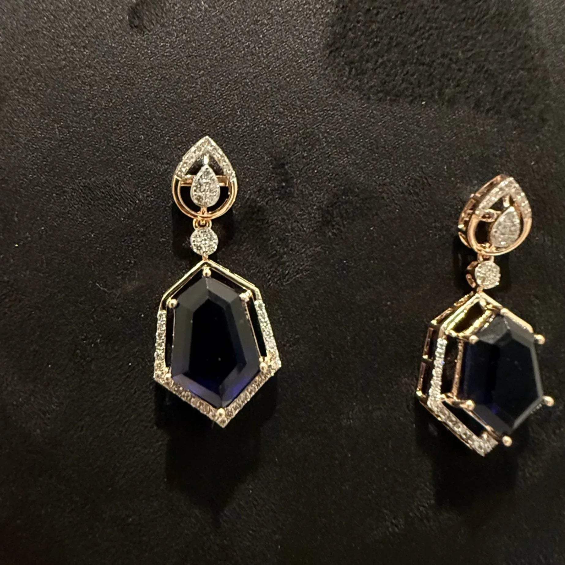 A gold diamond necklace with geometric matching earrings displayed on a mannequin bust.