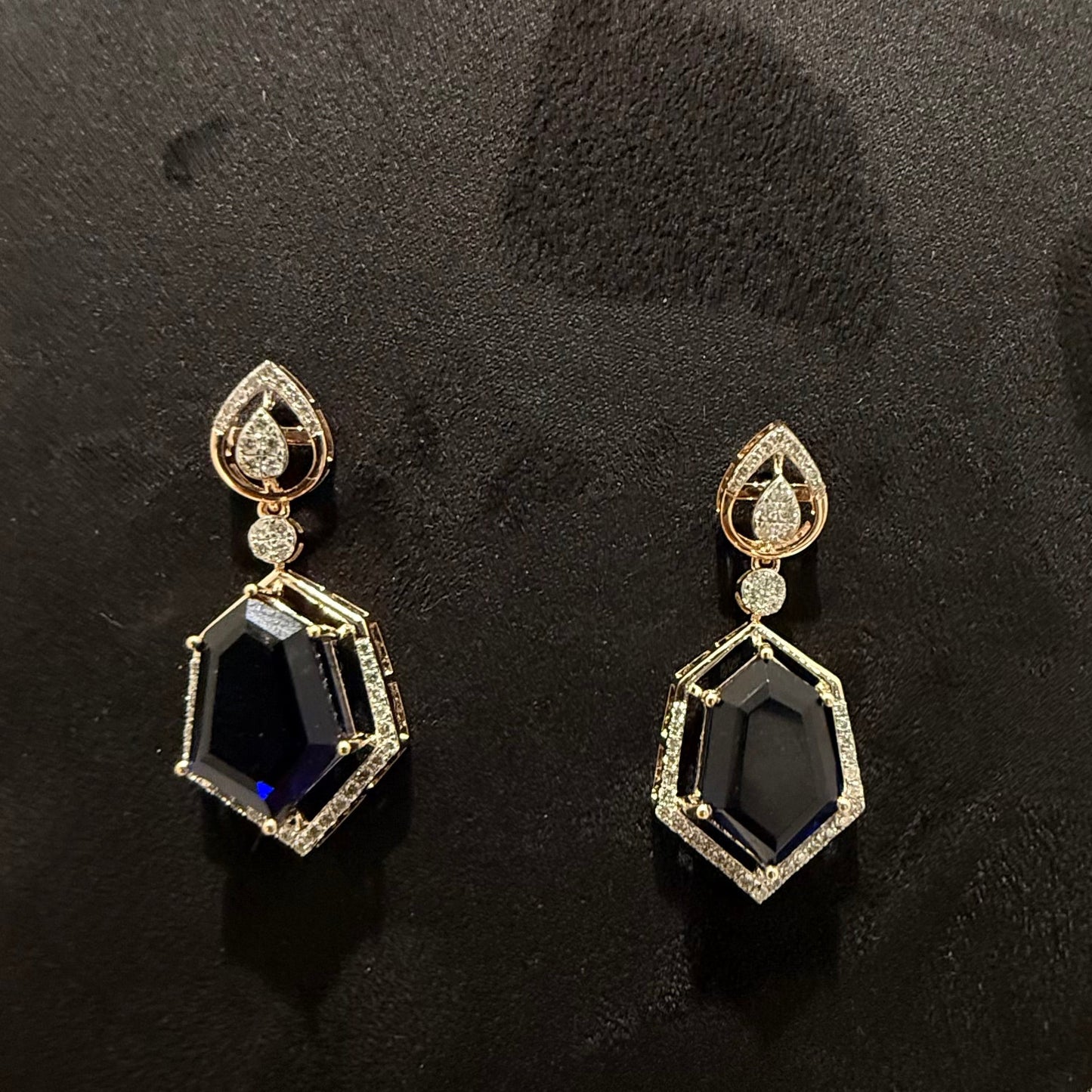 A gold diamond necklace with geometric matching earrings displayed on a mannequin bust.