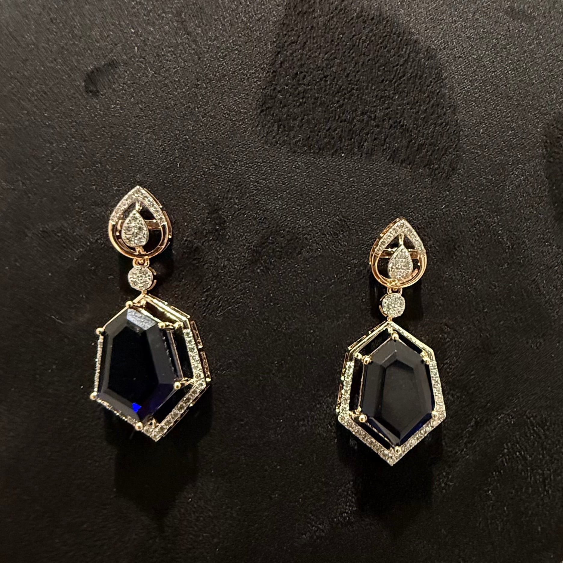 A gold diamond necklace with geometric matching earrings displayed on a mannequin bust.