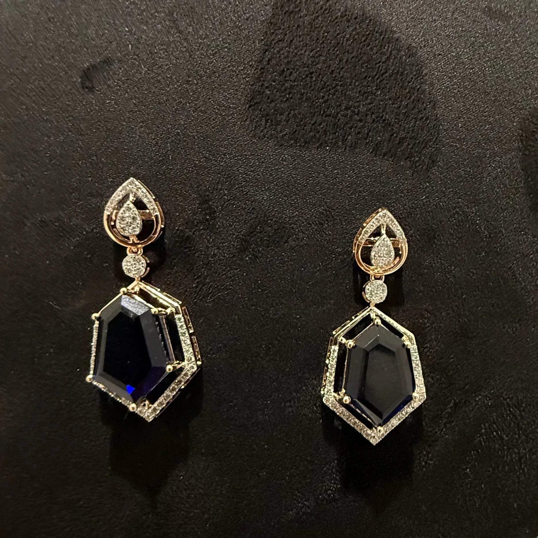 A gold diamond necklace with geometric matching earrings displayed on a mannequin bust.
