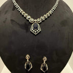 A gold diamond necklace with a geometric pendant and matching earrings displayed on a mannequin bust.